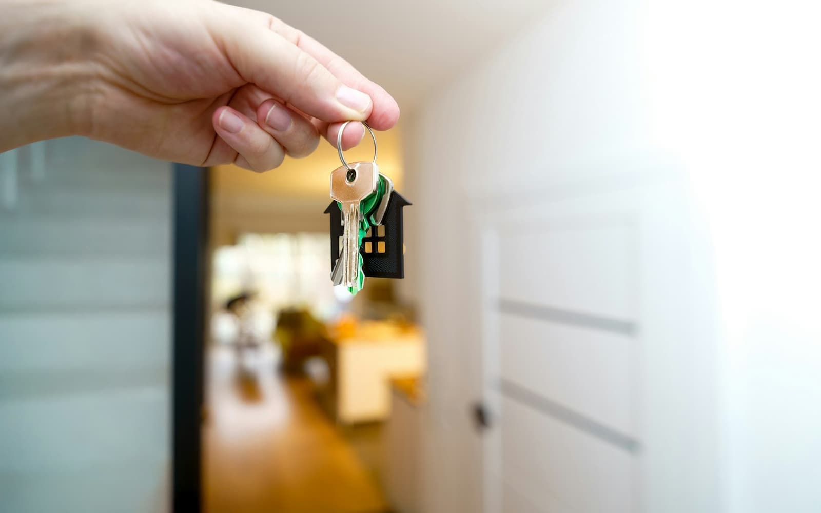 A hand holding house keys in a hallway