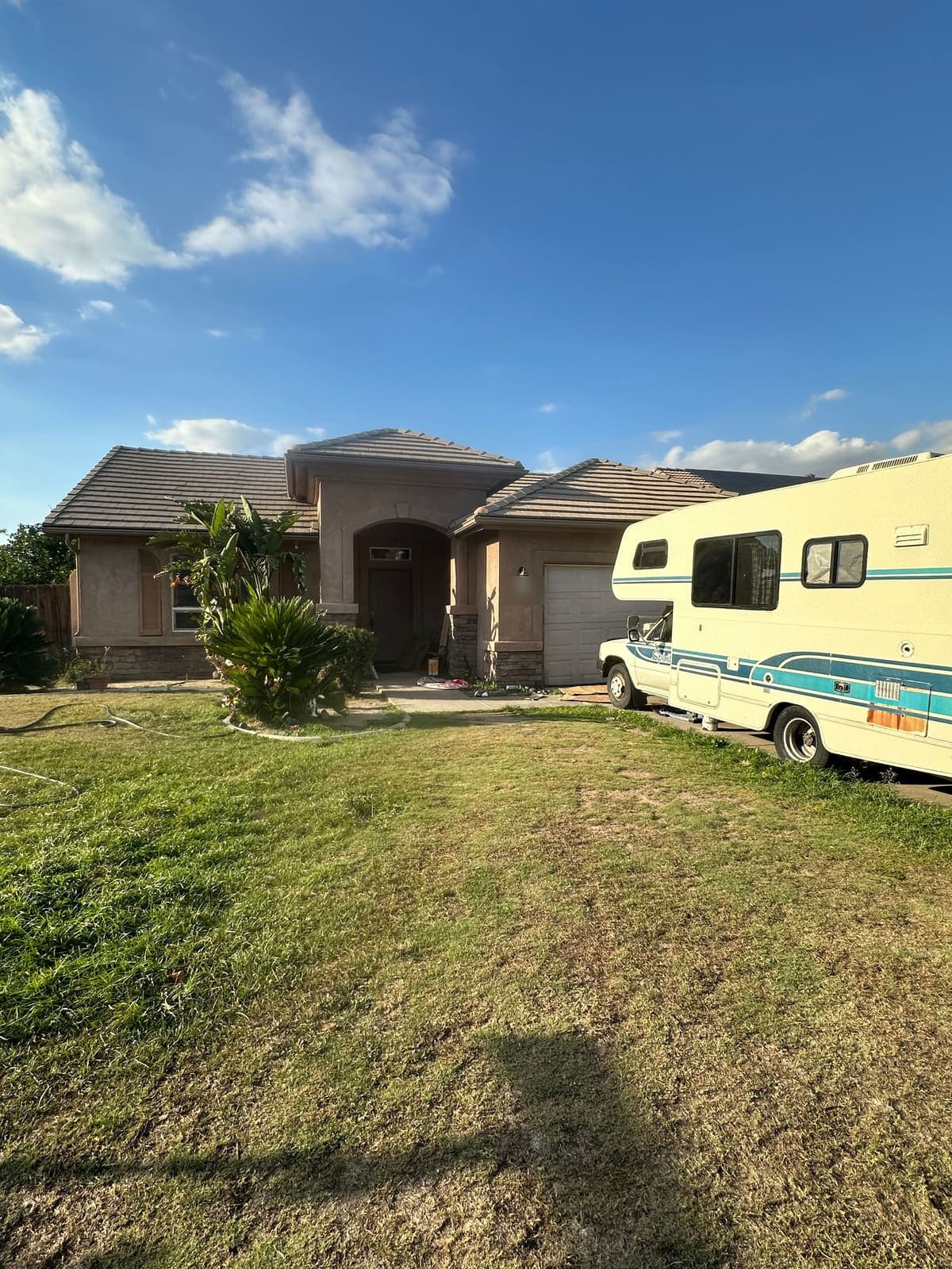 A stucco house with a motorhome parked in the driveway