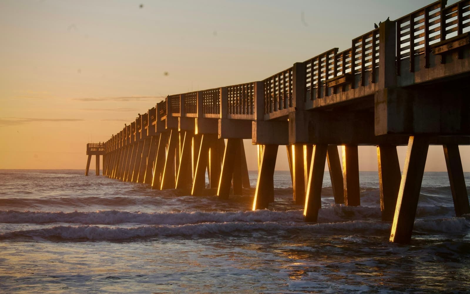 A wooden pier over the ocean at sunrise
