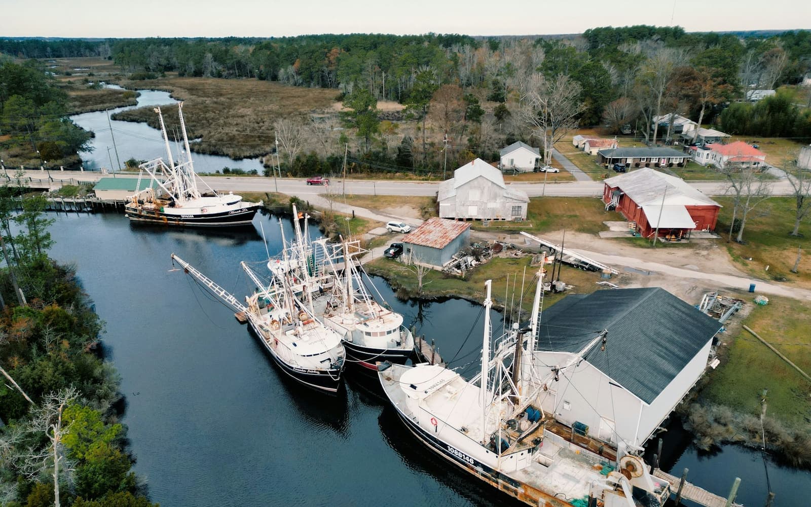 Fishing boats tied up along a coastal waterway, seen from the air