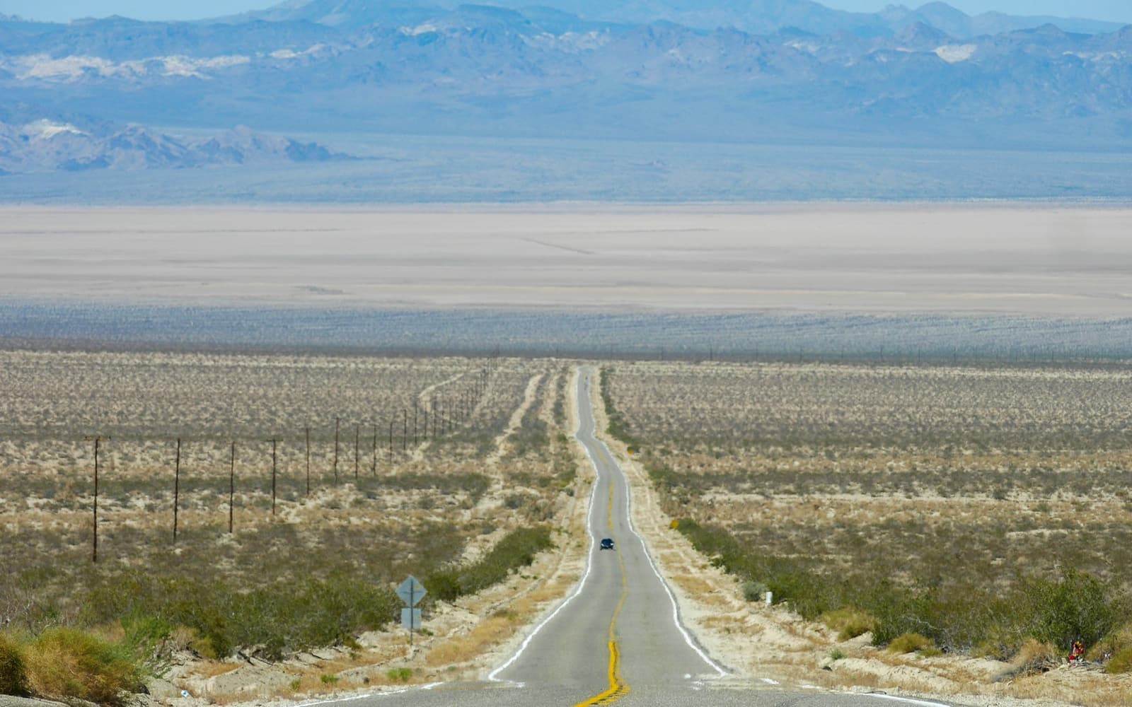 A straight road crossing the high desert toward the mountains