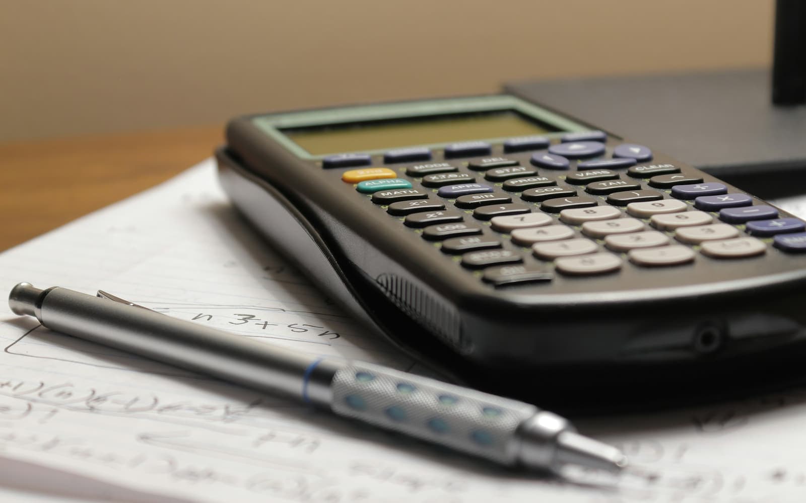 A calculator and a pen on handwritten notes